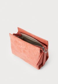 Sac à main en velours corail avec fermeture éclair, de forme rectangulaire et une bandoulière amovible. L'intérieur est doté d'une doublure beige subtile et d'une poche zippée.