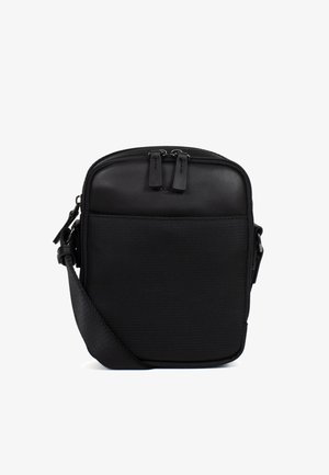 Kompaktowa czarna torebka na ramię z przednią kieszenią na zamek, regulowanym paskiem i podwójnym zamkiem błyskawicznym u góry.