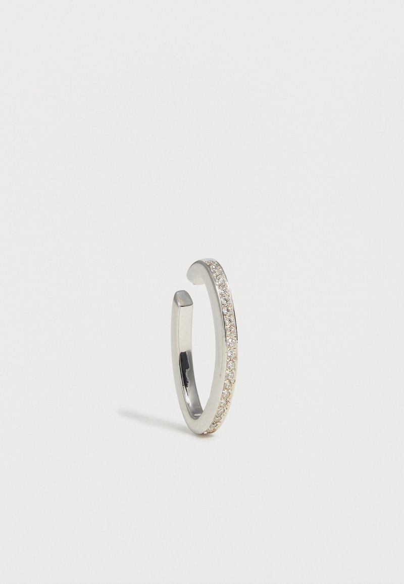 Ασημένια ανοιχτή κρίκος σκουλαρίκι με σειρά μικρών διαφανών πετρών κατά μήκος της εξωτερικής άκρης, εμφανίζεται σε λευκό φόντο.