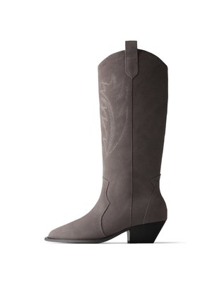 Botte western haute en daim gris avec talon noir incliné et motif de feuille décoratif cousu sur la tige.