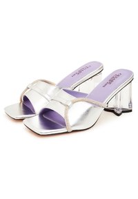 Sandales à talons hauts en métal argenté avec des talons blocs transparents, des bouts carrés et une sangle décorative. Équipées d'une semelle intérieure lilas avec un branding.
