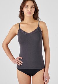 Grijze cami met verstelbare bandjes en een kantafwerking langs de halslijn. Zacht, rekbaar materiaal met een aangesloten silhouet. Zwarte slip zichtbaar.