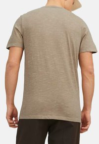 Lysebrunt kortærmet t-shirt med rund halsudskæring. Blød tekstur med et subtilt meleret mønster og en afslappet pasform.