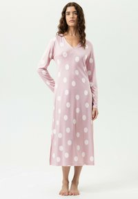 Langes rosa Nachthemd mit weißen Punkten, mit V-Ausschnitt und langen Ärmeln. Verfügt über einen seitlichen Schlitz und eine glatte Stoffstruktur.