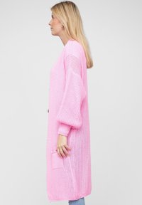 Cardigan lungo aperto in maglia rosa chiaro con vestibilità comoda, maniche lunghe a palloncino e tasca frontale.