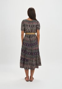 Maxi sukienka z krótkimi bufkami, kwiatowy wzór w odcieniach różu, bieli i granatu; ściągnięta talia złotym paskiem; zwiewna spódnica.