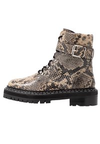 Bottes cheville lacées en similicuir effet peau de serpent avec un motif beige et noir, dotées d'une semelle noire épaisse et d'un détail de boucle argentée.