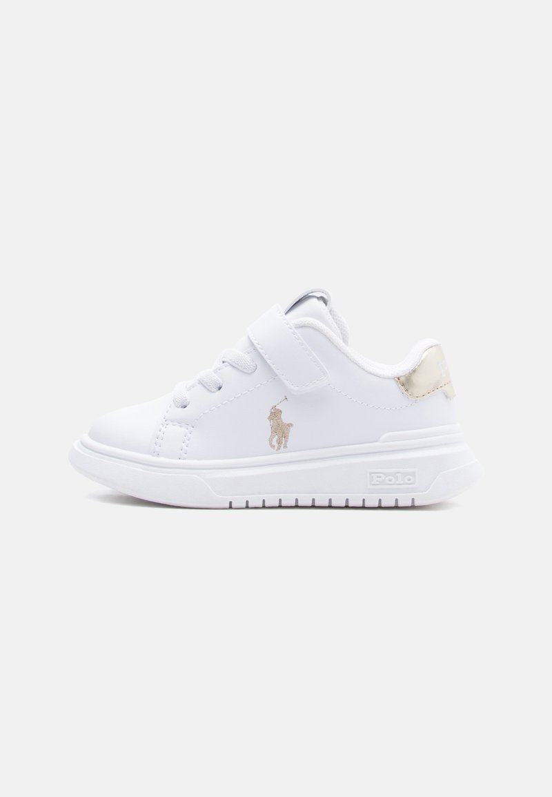 Zapatilla blanca para niños con cordones y tira de velcro, logo Polo dorado en el costado y detalle dorado en el talón, suela plana.