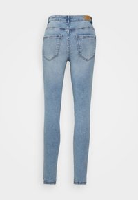 Jeans slim fit de cor azul claro feitos de denim, com um design de cinco bolsos e uma textura suave, apresentando uma etiqueta na cintura.