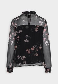 Blouse noire à motifs floraux avec manches longues transparentes, col à volants et ouverture en forme de goutte au dos; présente des motifs de fleurs roses et blanches sur le tissu.