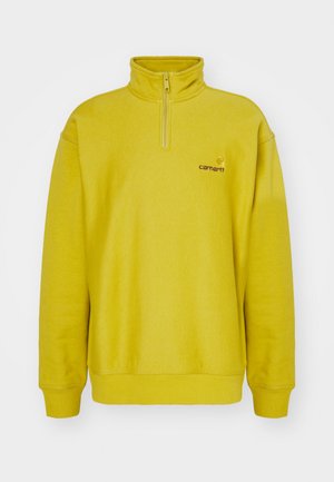 Gelber Fleece-Pullover mit einem halben Reißverschluss, gerippten Bündchen und einem gestickten Logo auf der linken Brust. Weiche Textur.