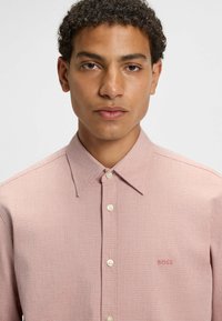 Lichtroze button-up shirt met textuurstof, spreidkraag en witte knopen. Bevat een klein, geborduurd "BOSS" logo op de borst.