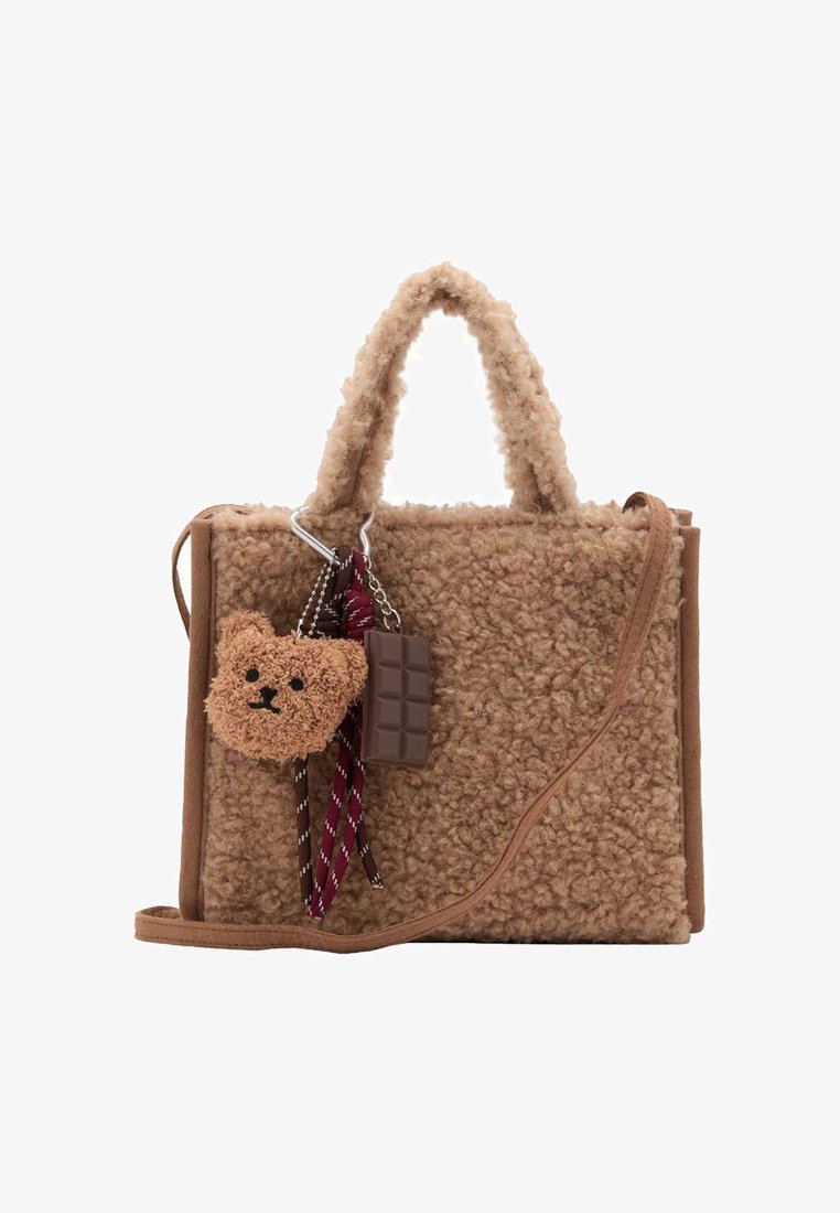 Brun faux fur handväska med korta handtag, avtagbar björn- och chokladberlock, samt en axelrem. Rektangulär form med mjuk textur.