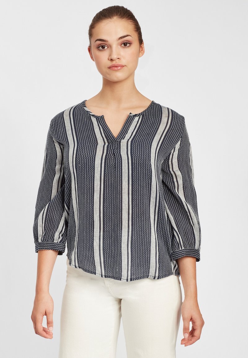 Marineblå og creme-stribet bluse med en notch-udskæring, trekvartærmer og letvægtsstof, der har et struktureret mønster.