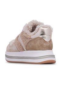 Beige suède sneaker met een fluffy textuur, zilveren metallic accenten en een witte tussenzool. Opvallende gebogen vorm bij de hiel en zachte voering.