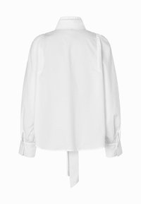 Bílá košile s dlouhým rukávem, vysokým límečkem, manžetami na knoflíky a tkaným kravatou visící ze zadního lemu.