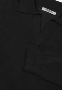 Czarna koszulka polo z wąskim kołnierzykiem, wykonana z miękkiego, teksturowanego materiału. Ma małą metkę "DAN JOHN" blisko kołnierzyka oraz prążkowane mankiety.