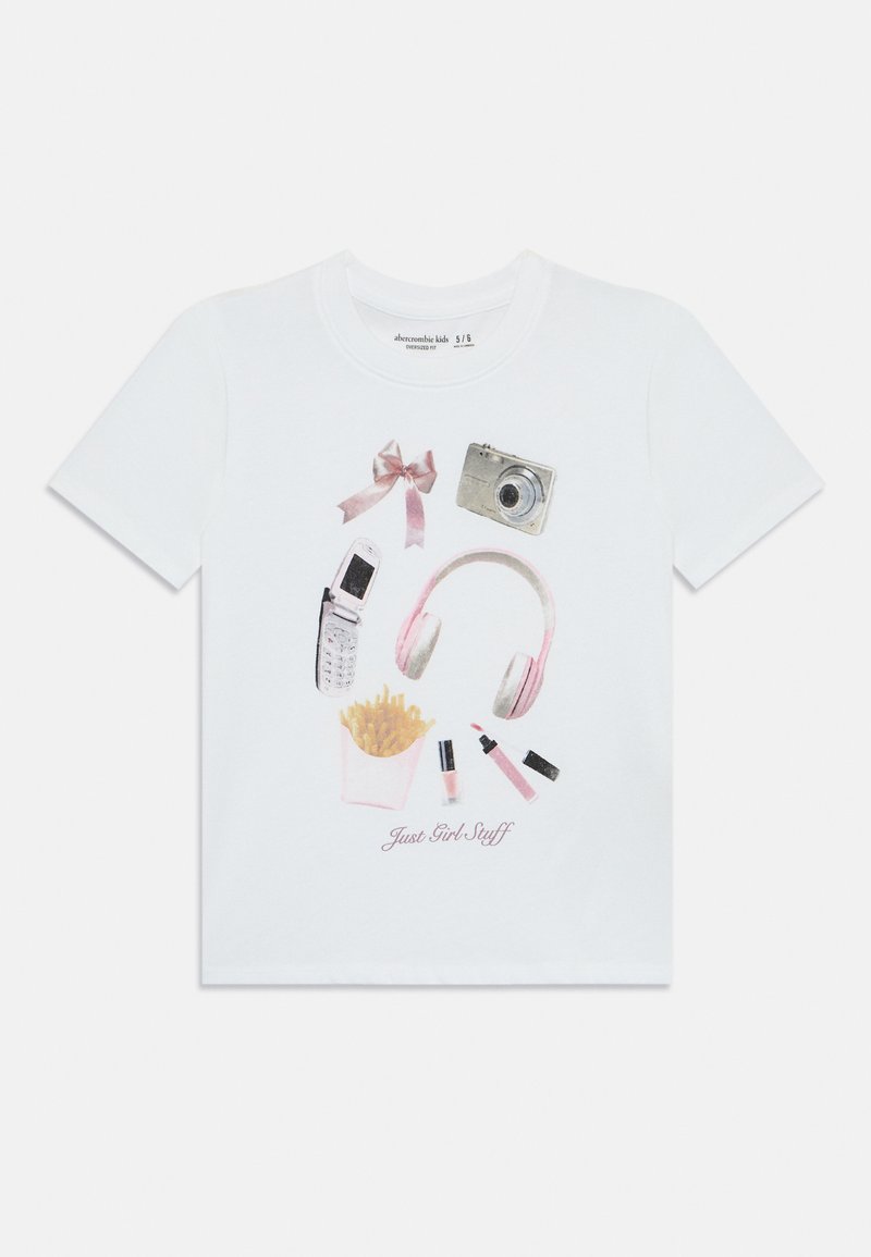T-shirt en coton blanc avec un imprimé graphique représentant un appareil photo, des écouteurs, un téléphone portable, du rouge à lèvres, des frites et un nœud rose, intitulé "Just Girl Stuff".