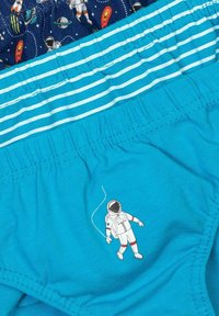 Tri par kidovskih hlačk: ena z vesoljskim vzorcem, druga z modro-belimi črtami in enobarvne turkizne, ki vsebujejo grafiko astronavta.
