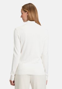 Fehér, hosszúujjú pulóver bordázott textúrával, hajtogatott gallérral és gombos díszítéssel a mandzsettákon. Puha, testhezálló kialakítás.