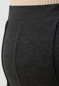 Tmavošedá sukňa z elastického materiálu s hladkou textúrou, elastickým pásom a detailami na bočných švoch. Jednoduchý a priliehavý dizajn.