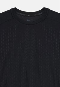 Čierne športové tričko Nike s krátkymi rukávmi, s textúrovaným dizajnom vertikálnych pruhov a okrúhlym výstrihom. Mäkký, elastický materiál.