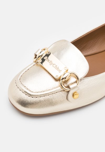 Goldfarbene metallic Lederloafer mit einer rechteckigen goldenen Hardware-Akzent mit graviertem Branding, runder Spitze und gestickten Details.