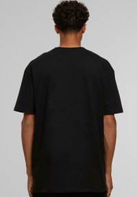 Sort bomulds t-shirt med en afslappet pasform, korte ærmer og crew neck. Bagsiden viser en glat tekstur og minimale designdetaljer.