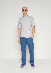 Tricou gri cu mânecă scurtă, pantaloni din denim albastru, adidași purpurii și ochelari de soare cu tentă purpurie. Design simplu, cu o croială confortabilă.