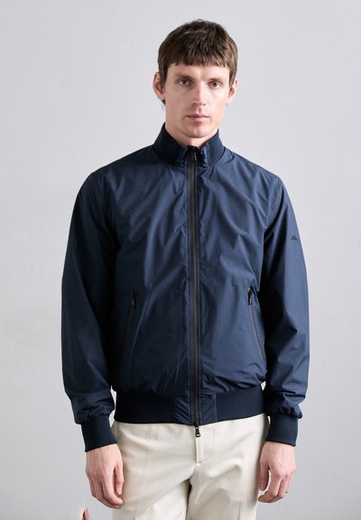 Navy lightweight bomber jacket with a stand-up collar, zippered front, side pockets, and elastic cuffs and hem. Smooth, water-repellent fabric.
