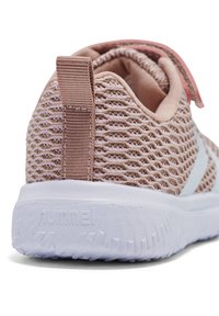 Zapatilla deportiva de malla rosa con parte superior texturada, suela blanca y una lengüeta en el talón. Presenta un sutil detalle de logo en blanco.