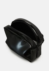 Černá, lesklá kosmetická taška vyrobená z hladkého materiálu, s uzávěrem na zip a strukturovaným tvarem s minimalistickým designem.