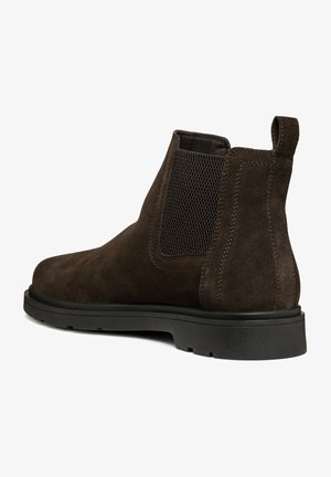 Botín Chelsea de ante marrón con un panel lateral elástico texturizado y una pestaña para el tirador. Cuenta con una suela de goma negra resistente y costuras en contraste.
