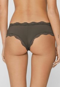 Slip hipster marroni con bordo in pizzo, dalla texture morbida e liscia e bordi smerlati, che mettono in risalto un design delicato e una forma aderente.