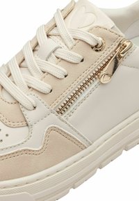 Beige és fehér sneaker, mely nubuk és bőr anyagokból készült, fűzős kialakítással, oldalsó cipzárral és arany színű hardware-rel, valamint texturált gumitalppal.