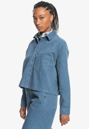 Lichtblauwe corduroy shirt met een cropped ontwerp, knoopsluiting aan de voorkant, borstzak en kraag. Heeft een geribbelde textuur en een relaxte pasvorm.