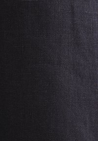 Gros plan de la texture d’un tissu tissé bleu marine foncé avec des fils serrés et des variations subtiles de teintes.