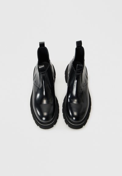 Botine Chelsea din piele neagră, cu panouri laterale elastice, vârfuri rotunjite și accente texturate pe laterale. Talon gros din cauciuc pentru durabilitate.