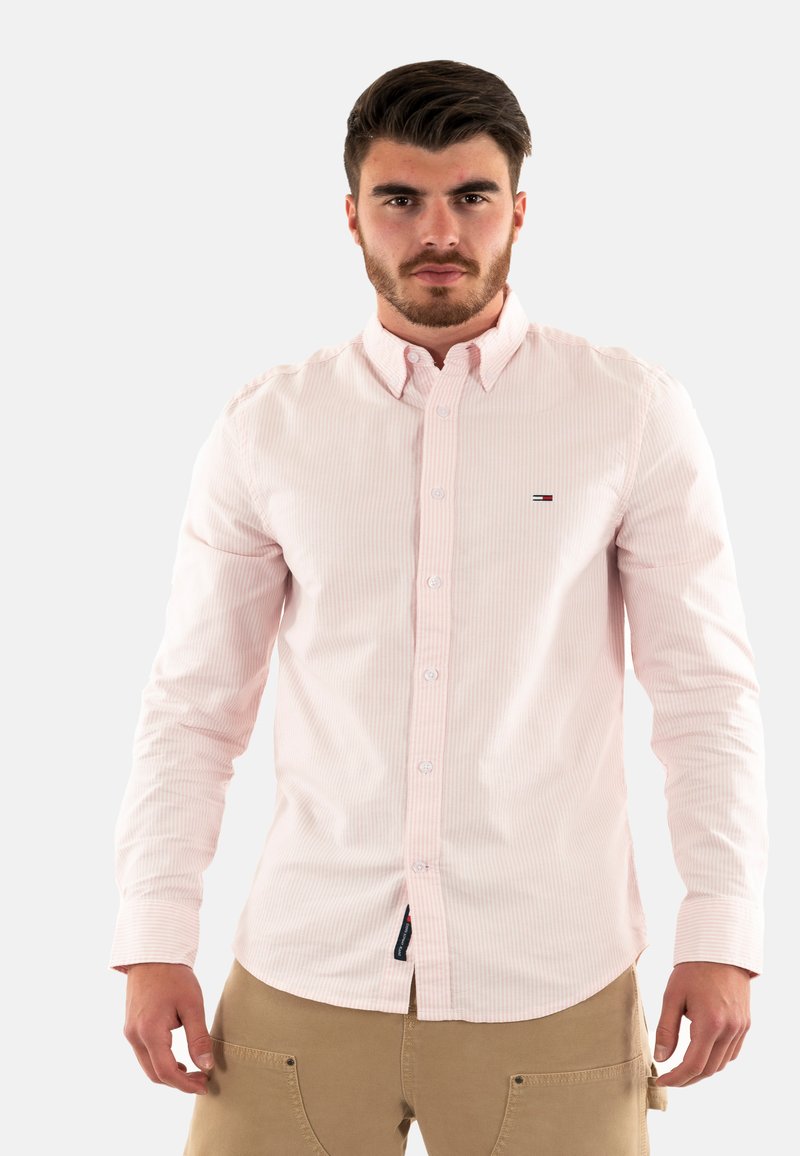 Chemise à rayures rose clair avec des boutons, fabriquée en coton, dotée d'un col pointu, avec un petit logo sur la poitrine gauche et des boutons blancs.