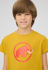 Geel katoenen T-shirt met een rode mammoetafdruk binnen een ronde rand. Het shirt heeft korte mouwen en een ronde halslijn.