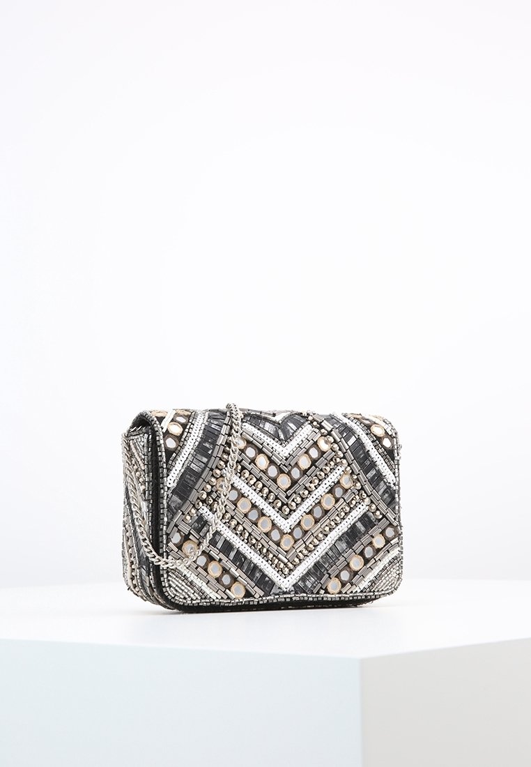 Borsa a mano in perline di colore nero, argento e beige. Presenta un motivo a zigzag, una tracolla a catena e decorazioni decorative sulla superficie.