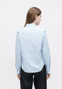 Ανοιχτό γαλάζιο πουκάμισο με ρίγες, κλασικό γιακά, μανσέτες με κουμπιά και απαλό ύφασμα. Διαθέτει κυρτή βάση και χαλαρή εφαρμογή.