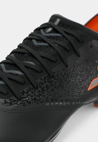 Pantofii de fotbal negri au un material texturat cu un design infuzat cu carbon și accente portocalii. Include șireturi negre și o talpă sintetică.