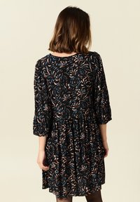 Schwarzes Kleid mit floralem Muster in Blau, Pink und Grün. Dreiviertelärmel und eine geraffte Taille, aus leichtem Stoff gefertigt.