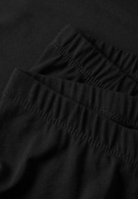Tissu en coton noir avec élastique froncé à la taille, offrant une texture lisse et une coupe ample, idéal pour un port confortable.