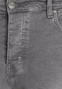 Gray denim jeans featuring a smooth texture, visible stitching, a button closure, and standard five-pocket design.