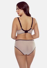 Hautfarbene Unterwäsche bestehend aus einem BH mit verstellbaren Trägern und einem Hakenverschluss, kombiniert mit passenden hochgeschnittenen Panties, die schwarz umrandet sind.