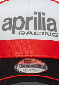 Ρυθμιζόμενο καπέλο με λευκό μπροστινό μέρος, κόκκινη γείσο και μαύρο πίσω μέρος. Φέρει την επιγραφή "aprilia RACING" με γκρι γράμματα και μια ετικέτα "New Era 9FORTY".