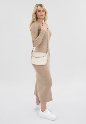 Robe en tricot beige à manches longues, silhouette ajustée ; associée à un sac bandoulière crème et des baskets blanches. Texture lisse, design minimal.