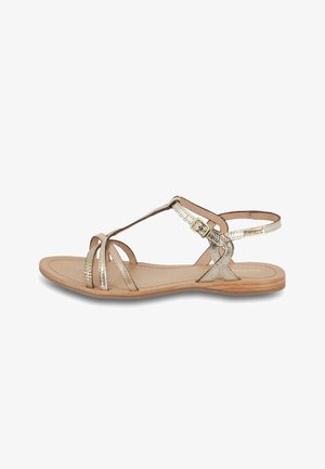 Gold metallic strappy sandals with a flat wooden sole, featuring adjustable ankle strap and textured bands across the foot.